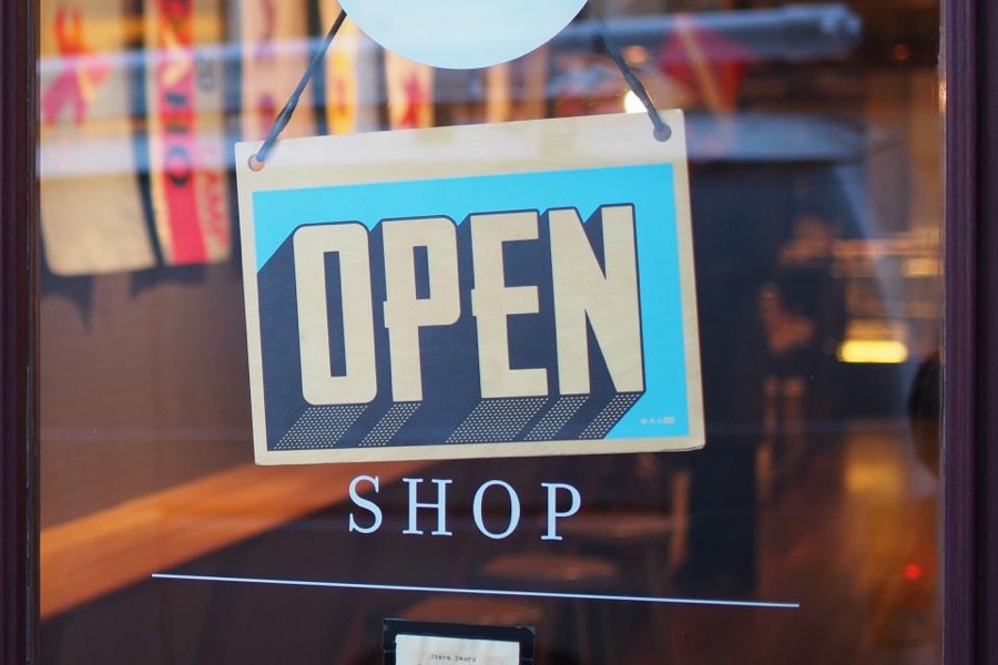 An open sign hanging in the window of a local shop